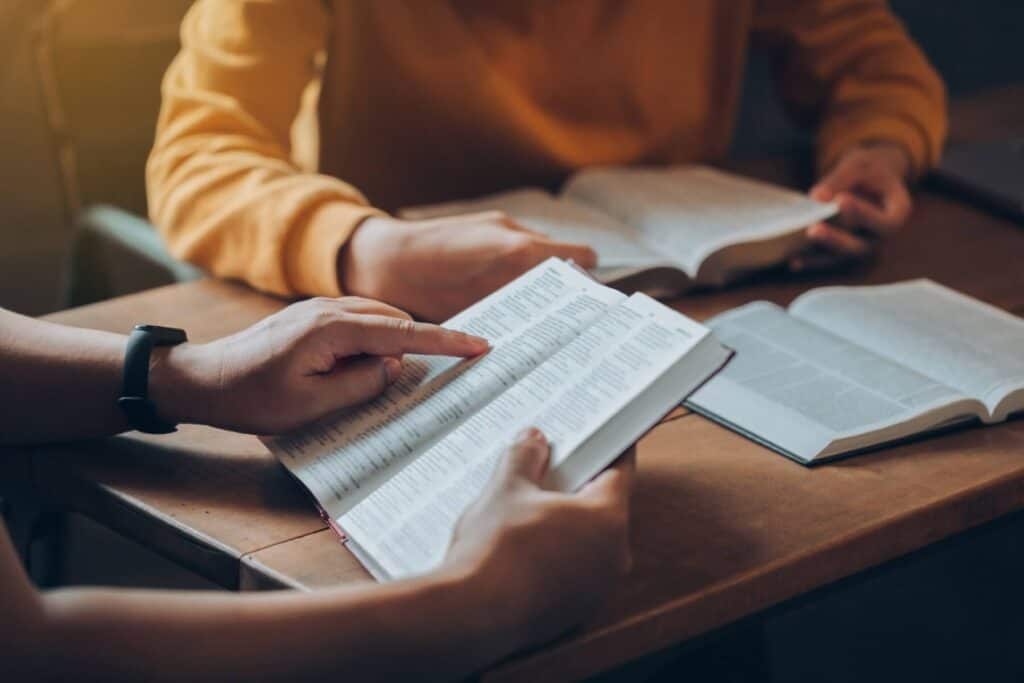 Students sitting at a table reading religious text